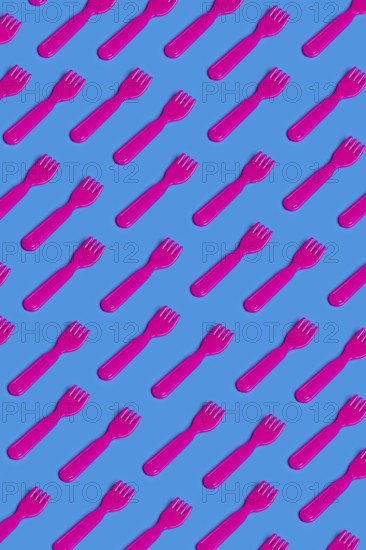 Rows of pink plastic cutlery on a blue background symbolizing the artificiality and environmental