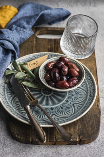A tasteful arrangement of Greek BBQ olives on a ceramic plate, accompanied by a glass, rustic