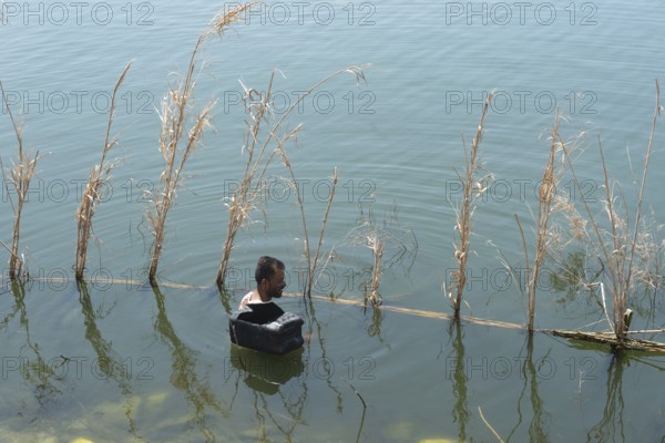 Rosetta, Egypt. June 27th 2024 An Egyptian fishermen checks his fish traps using wire baskets and