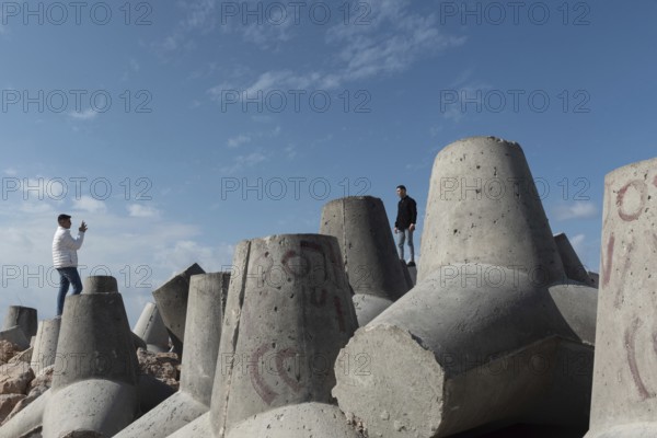 Alexandria, Egypt. December 1st 2022 Young Egyptian men take photographs on massive concrete blocks