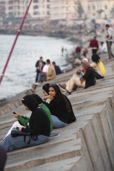 Alexandria, Egypt. December 1st 2022 Young Egyptian women sit on concrete sea defence walls in the