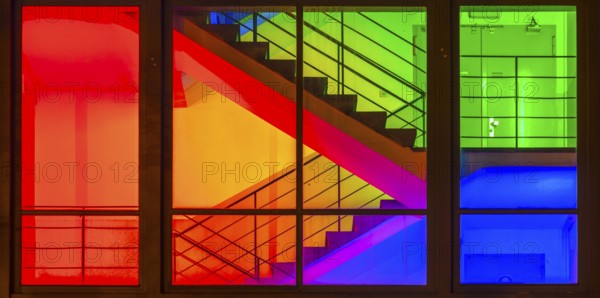View through the windows of a brightly lit staircase. Frankfurter Mainova AG building, city center,