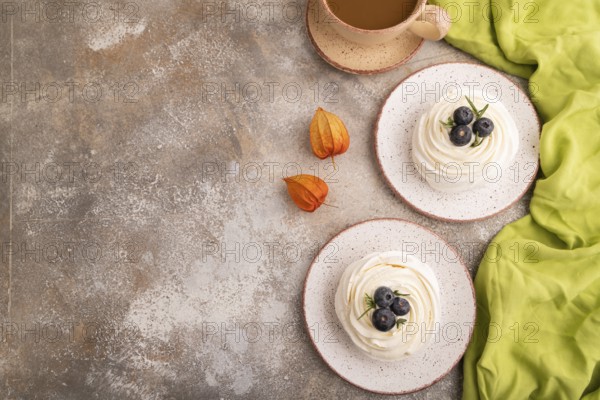 Pavlova Meringue dessert with crisp meringue and blueberry, cup of coffee, on brown concrete
