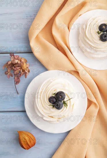 Pavlova Meringue dessert with crisp meringue and blueberry on blue wooden background with orange
