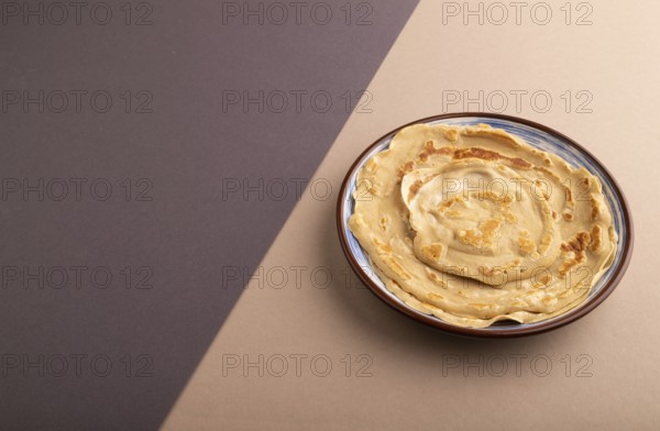 Stack of Plain Fried pancakes on gray and beige pastel paper background. side view, copy space