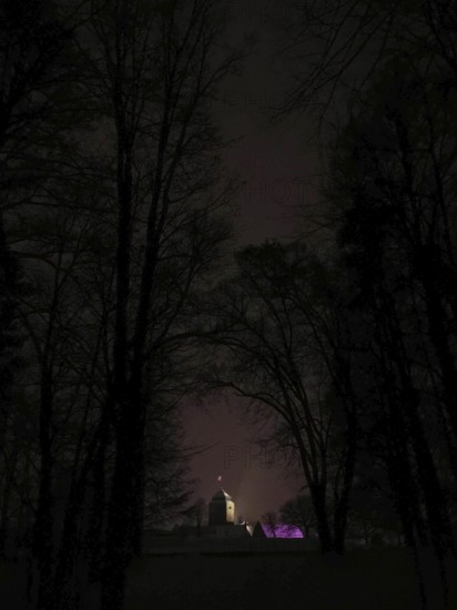 Building hidden in the dark, dimly lit Rosenberg Fortress surrounded by trees, Kronach, Frankenwald
