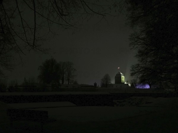 Dark, silent night scene with the dimly lit Rosenberg Fortress behind the trees, Kronach,