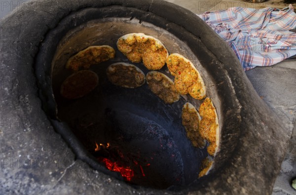 Delicious Turkish Biberli Ekmek Flat bread with red pepper paste cooking in a traditional oven in