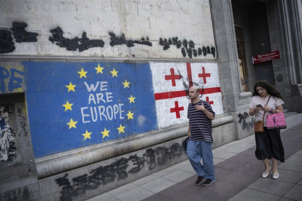Tbilisi, Georgia. August 26th 2025. Georgian people walk past the flags of Georgia and the European