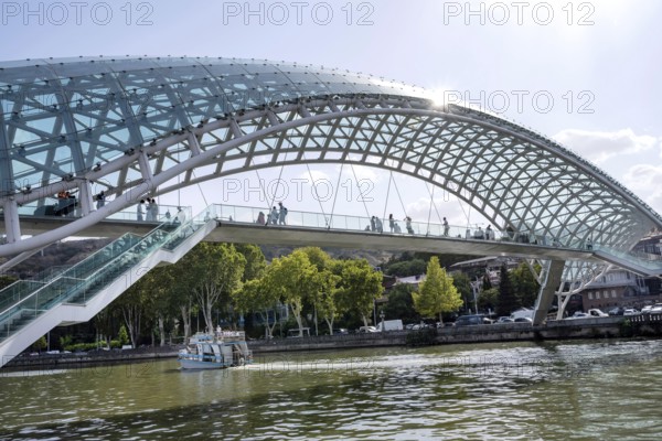 Tbilisi, Georgia. August 26th 2025. Tourists cross The Bridge of Peace over the Kura River also