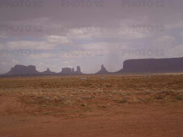 Wide, flat desert landscape with scattered rock formations and cloudy sky, Monument Valley, Navajo