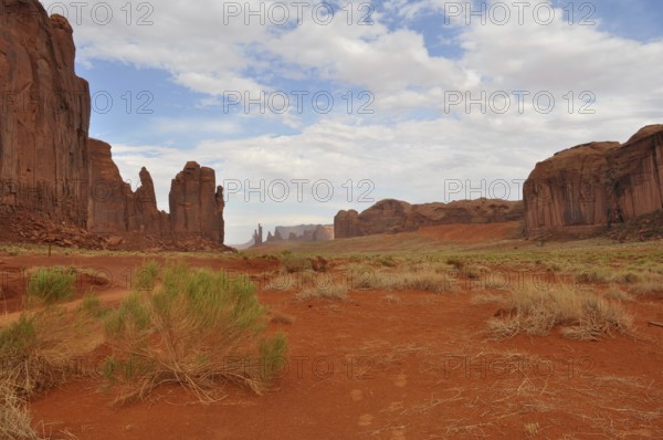 Wide valley with high rock walls surrounded by dry, red landscape, Monument Valley, Navajo Tribal