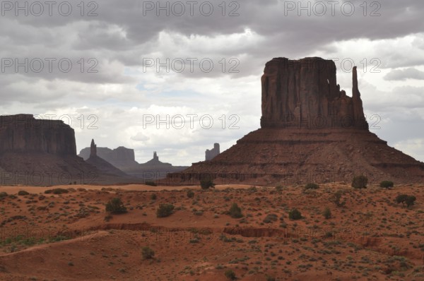 Dramatic view of a large rock formation under a cloudy sky in Monument Valley, Navajo Tribal Park,