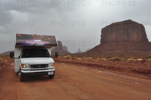 An RV on a road in Monument Valley surrounded by impressive rocks after a severe thunderstorm,