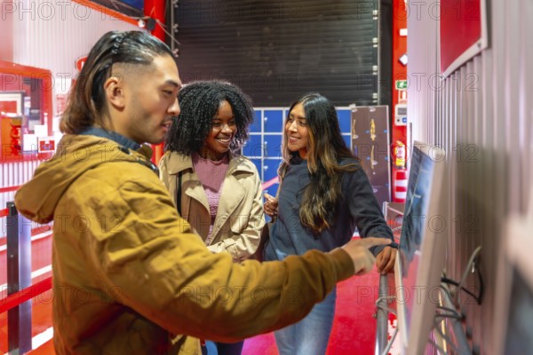 Diverse group of friends smiling and pointing at a touchscreen to select races and book indoor go
