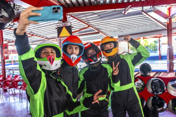 Group of four diverse friends wearing colorful helmets and racing suits, smiling and posing for a