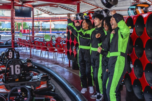 Diverse friends in racing suits celebrating with fists pumped up, feeling excited and happy after