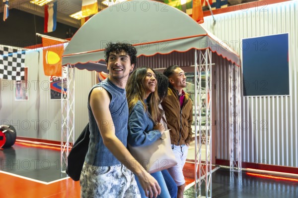 Diverse group of young adult friends smiling and laughing while watching an indoor karting track,