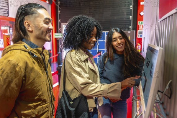 Diverse group of young adult friends laughing and talking while interacting with a self service