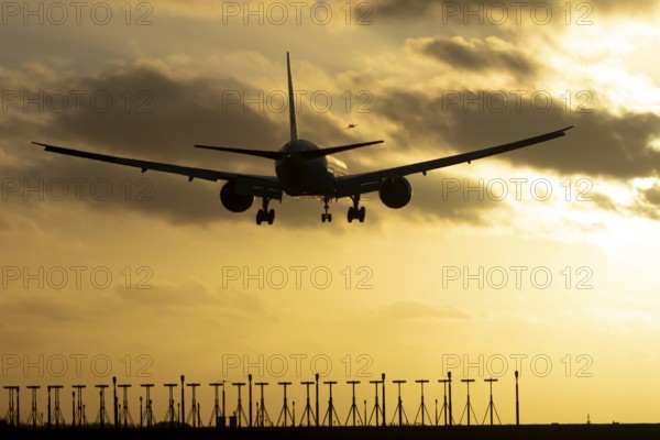 Boeing 777 commercial passenger jet aircraft in flight on approach to land over runway lights