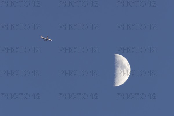 Airbus commercial passenger airliner jet aircraft of British airways in flight with the moon in the