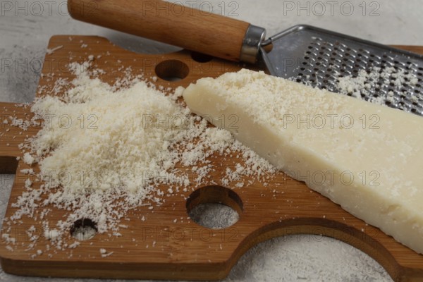Freshly sliced and grated cheese, parmesan cheese, Gran gusto. Grana padano. on a wooden chopping