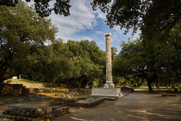 Column of the NikAntique Column in a wooded landscape of ruins under a blue sky, Archaeological