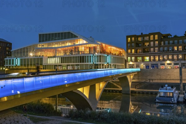 Primark on Maasboulevard and illuminated bridge across the city harbor in Venlo at dusk, the