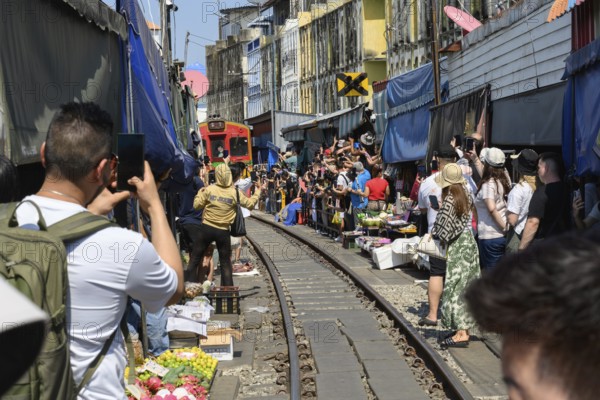 Mae Klong, Thailand. March 15th 2025. Tourists gather on the rail lines as the 14.30 train passes