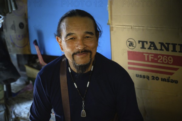 Mae Klong, Thailand. March 15th 2025. A smiling Thai market trader with an amulet necklace, at the