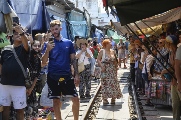 Mae Klong, Thailand. March 15th 2025. Tourists take photographs on the train lines as the 14.30