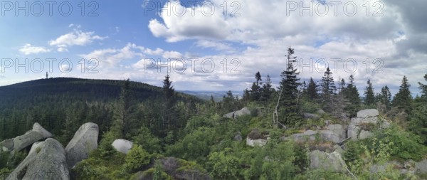 Panoramic view from Nusshardt over a wooded landscape with rocks and cloudy sky in the background,