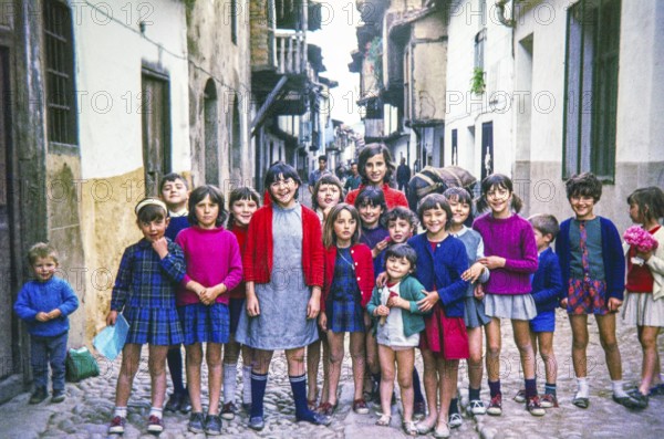 Group of children posing for photograph standing across a historic cobbled street, Portugal, Europe