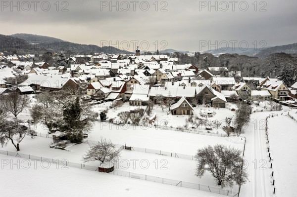 Snowy village with half-timbered houses and gardens under a grey sky, Herleshausen in northern