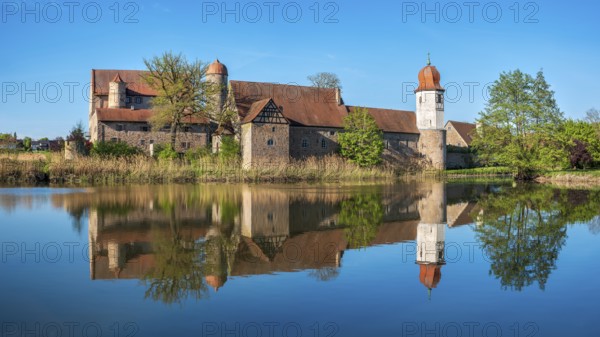 Perfect reflection of Sommersdorf Castle in a pond near Burgoberbach in the Altmühltal, Middle
