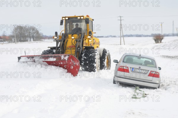 Car stuck in snow gets help from a loader to get free in Skurup municipality, Skåne county, Sweden,