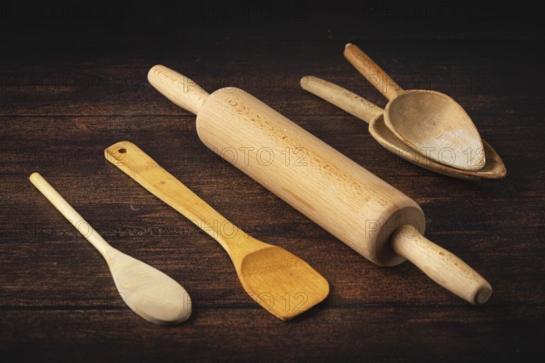 Rolling pin and wooden utensils on a dark wooden table in a rustic atmosphere