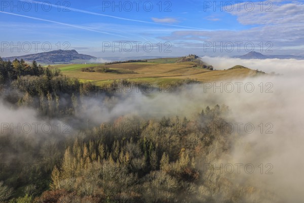 Foggy landscape in Hegau with hills and forests under a clear blue sky, Hohenkrähen castle ruins,