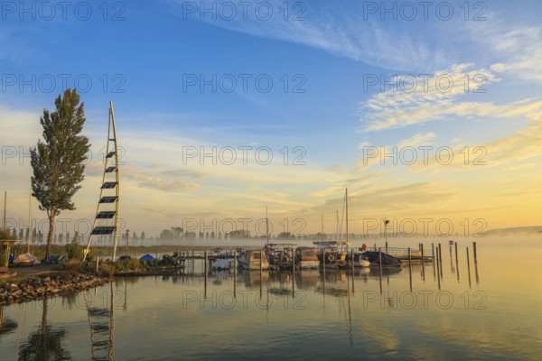 Lake Zell at sunrise with boats on a jetty and a clear sky with clouds, Lake Constance, Höri