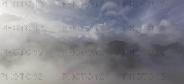 Thick blanket of clouds and fog over a mountain landscape with mystical sky, hiking in the High