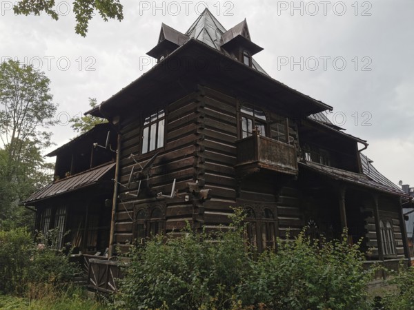 Old typical traditional Tatra wooden house with rustic architecture surrounded by trees under