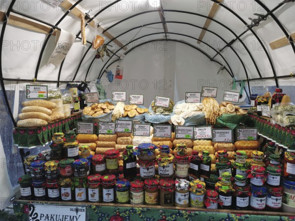 Colourful market stand with various types of jams and breads and local specialities under a tent,