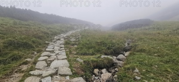 Rocky hiking trail through hilly, foggy landscape, Zakopane, hike to Kasprowy Wierch in the High