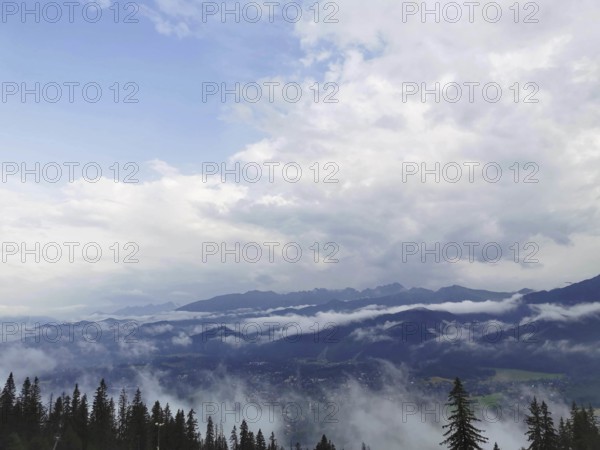 Extensive view of a foggy valley with mountains and cloud cover in the background, Zakopane, hiking