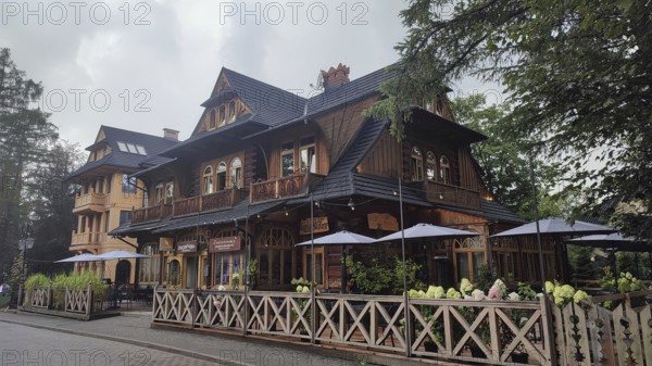 Charming restaurant in traditional Zakopane Tatra wood style with terrace and garden fence,