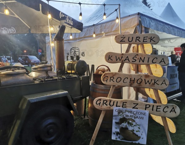 Street vendor with goulash cannon with traditional Polish food at night, illuminated with warm