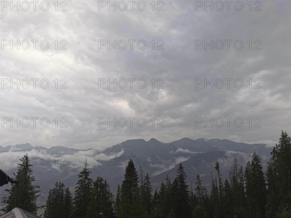View of a mountainous landscape with clouds and conifers wrapped in fog, Zakopane, hiking in the