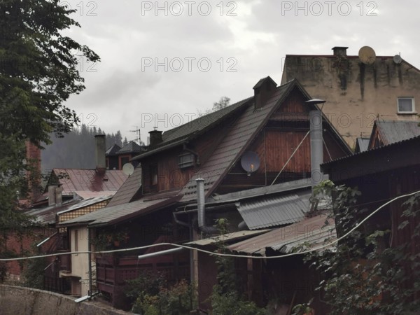Old wooden rural buildings with various roofs and satellite dishes on a cloudy day, Zakopane,
