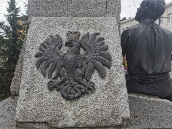 Stone monument with relief of the Polish white eagle, next to a human sculpture, Zakopane, hiking