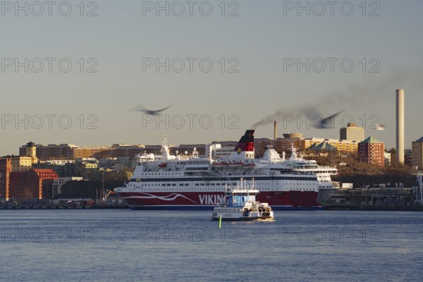 A ferry and a smaller city ferry on a river with an urban backdrop at dusk, Stockholm, Sweden